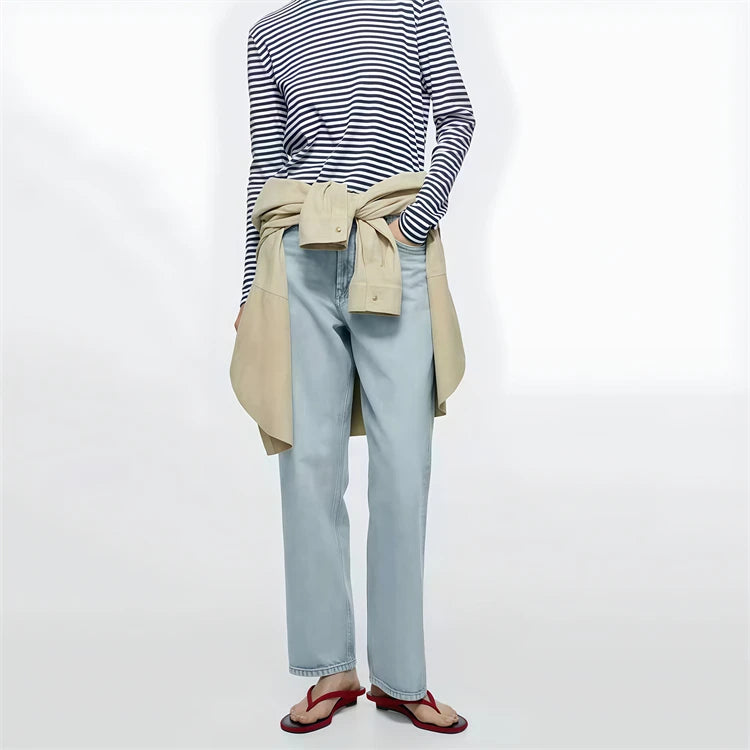 Person wearing a striped shirt, light blue jeans, beige cardigan, and red sandals on a white background