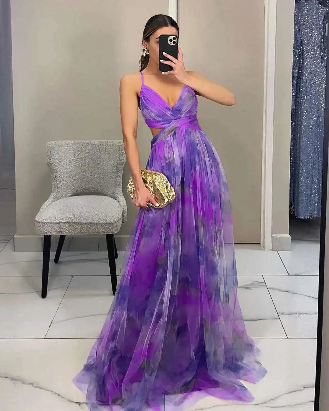 Woman in a purple evening gown taking a mirror selfie in a store.