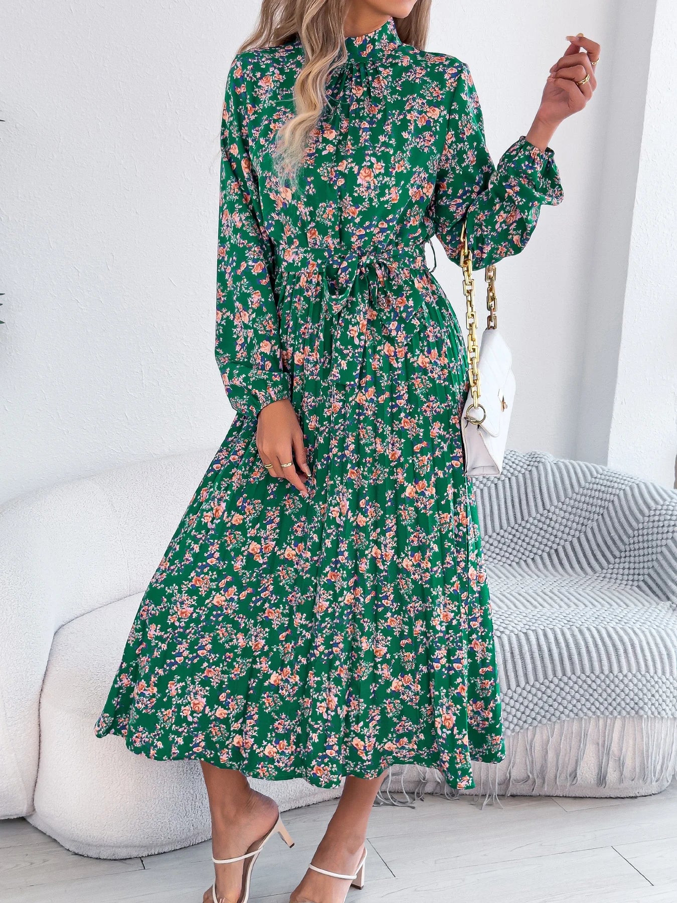 Woman wearing a green floral dress in a minimalistic room.