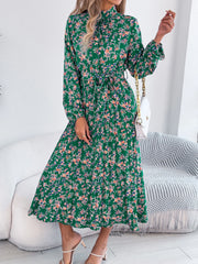 Woman wearing a green floral dress in a minimalistic room.