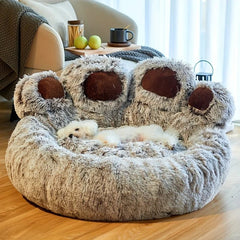 Fluffy pet bed shaped like a bear with a small white dog inside, in a cozy living room setting.
