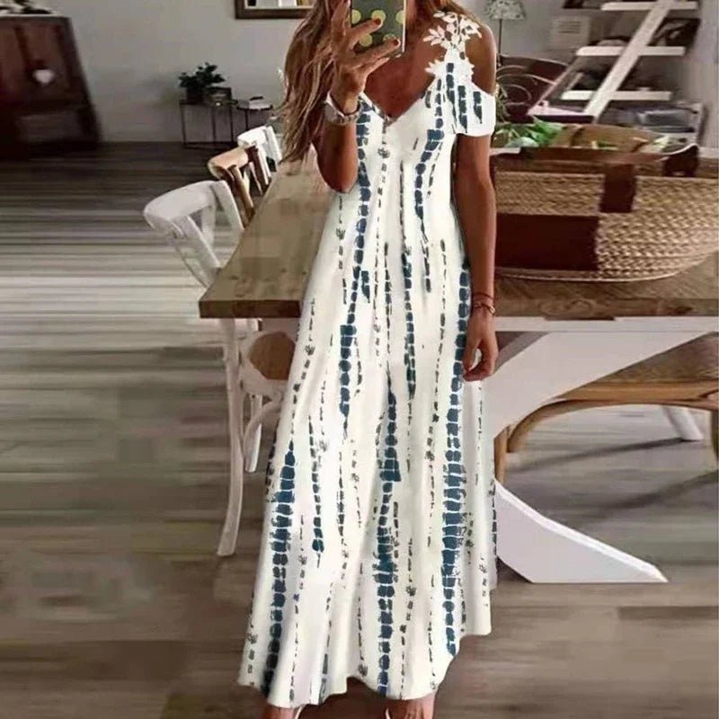 Woman wearing a white dress with blue patterns in a room with wooden flooring and furniture.