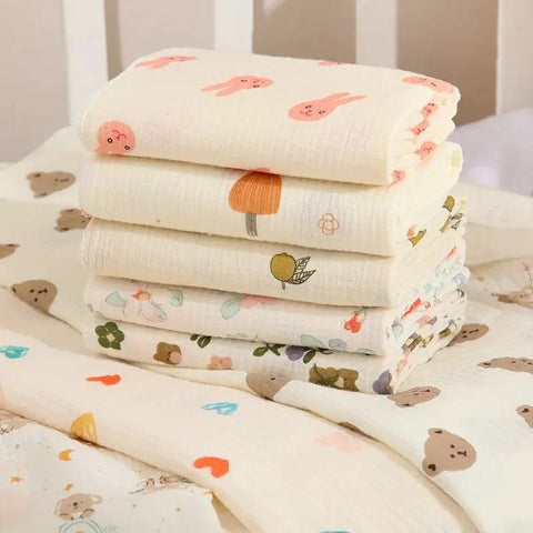 Stack of baby blankets with colorful patterns on a white surface