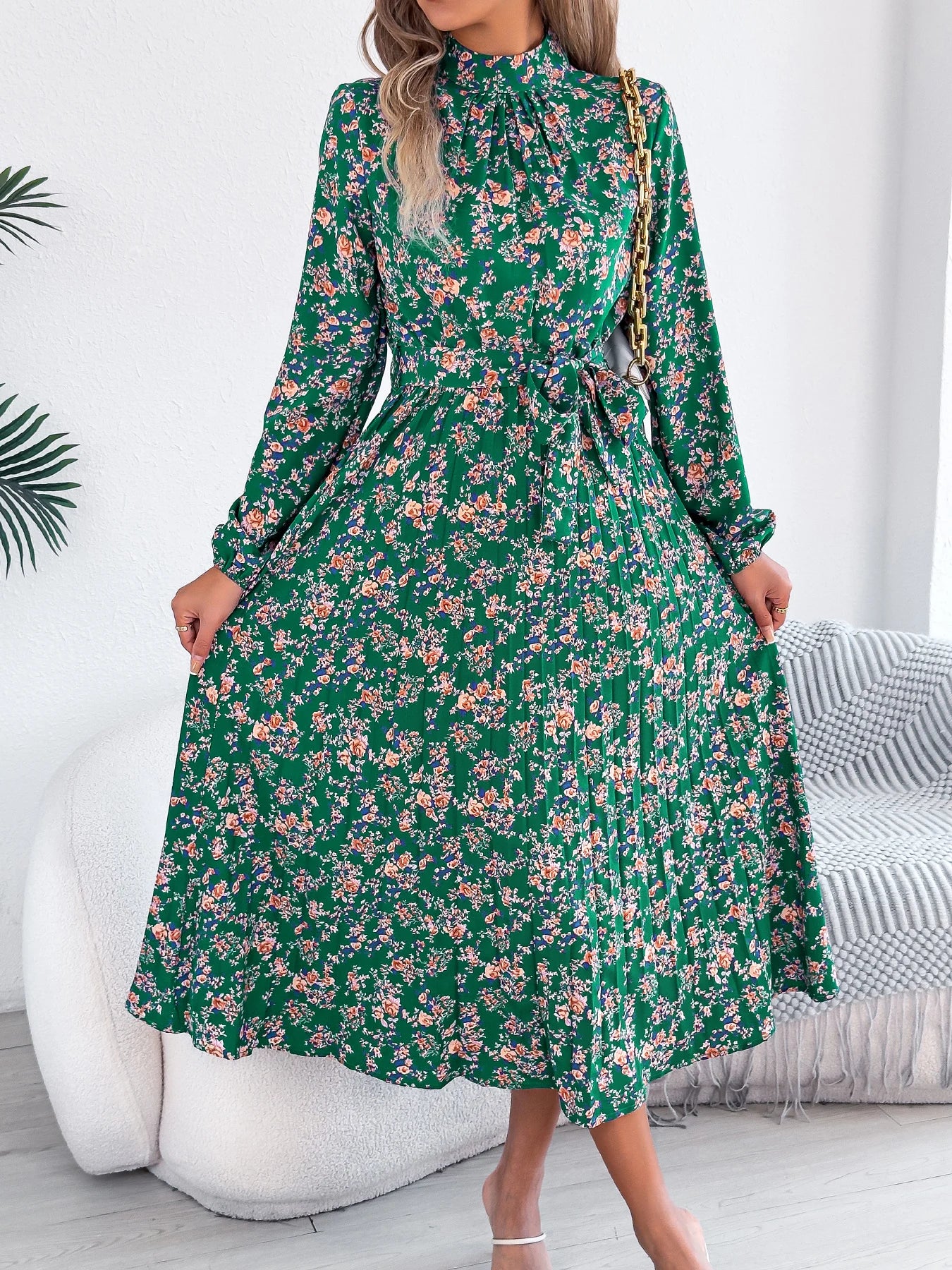 Woman wearing a green floral dress in a minimalistic room.