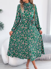 Woman wearing a green floral dress in a minimalistic room.