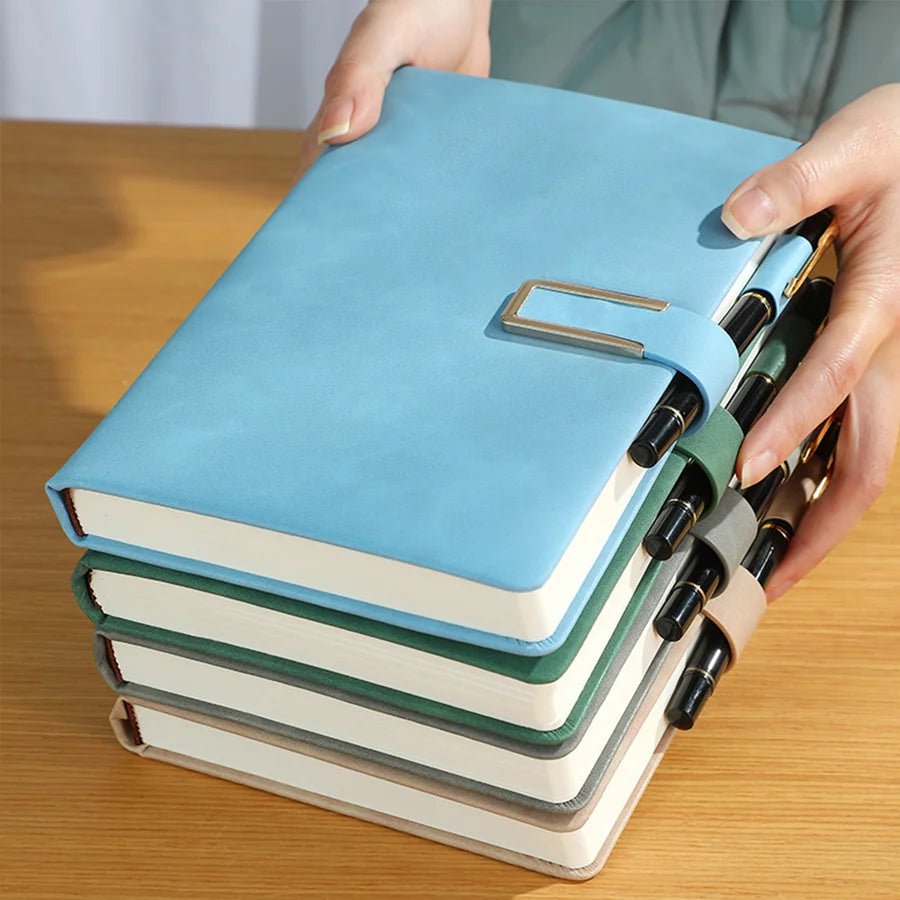 Stack of notebooks with a blue cover held by a person on a wooden surface
