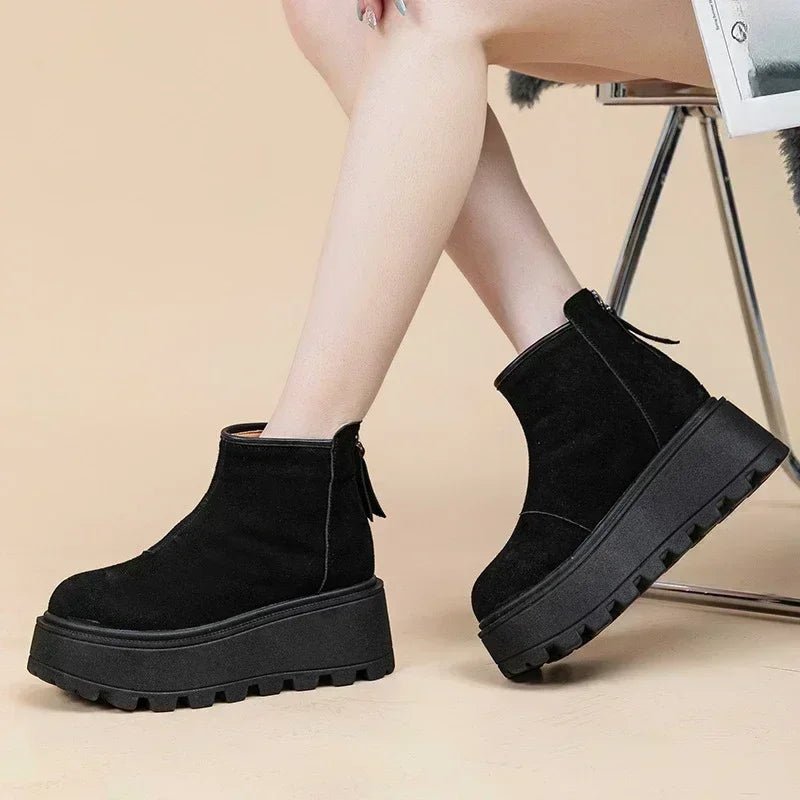 Black platform ankle boots worn by a person on a beige background