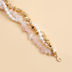 Multistrand bracelet with pearls and gold accents on a beige background