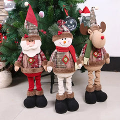 Three Christmas-themed decorations including a Santa Claus, snowman, and reindeer in front of a decorated tree.