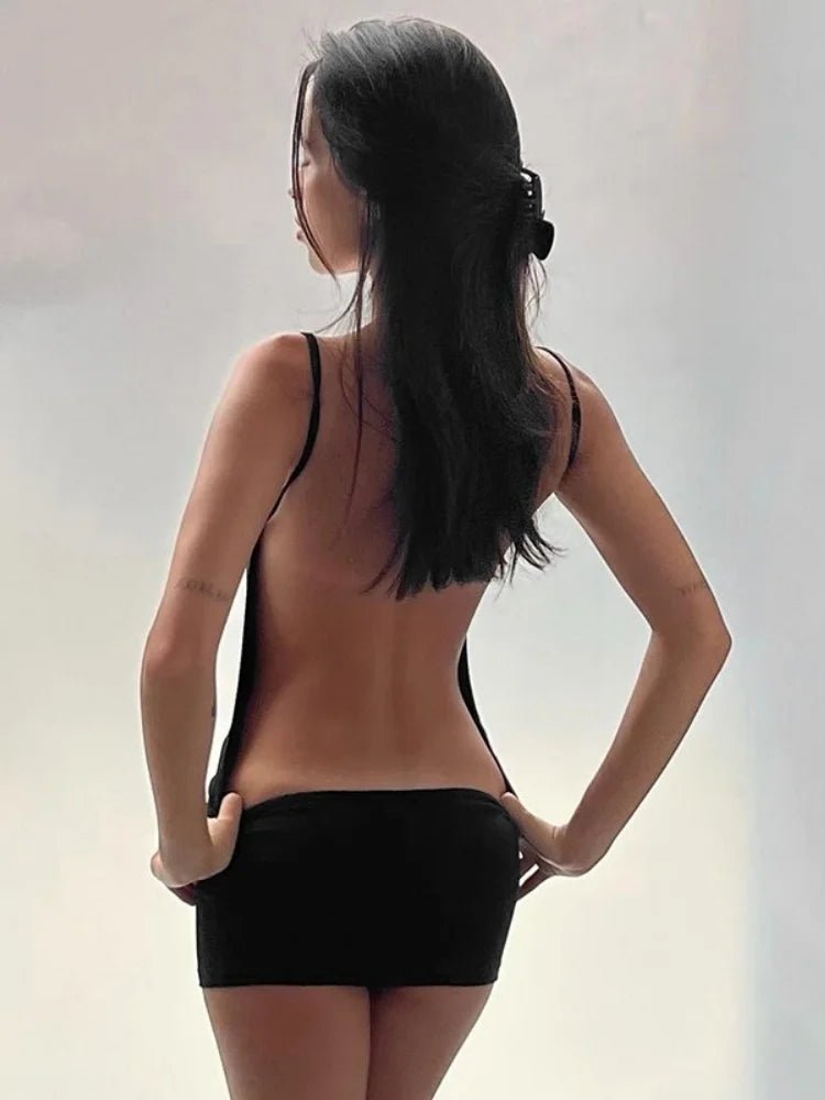 Woman wearing a black strappy top and black shorts against a plain background