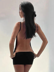 Woman wearing a black strappy top and black shorts against a plain background