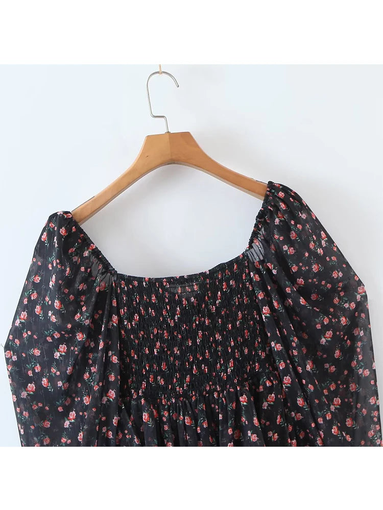 Black floral dress on a wooden hanger against a white background