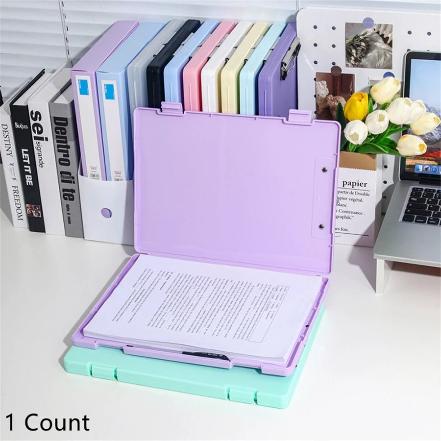 Colorful file folders on a desk with books and a laptop in the background