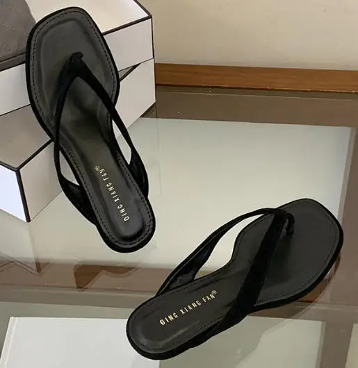 Black sandals with 'QING XIANG FAN' branding on a reflective surface.