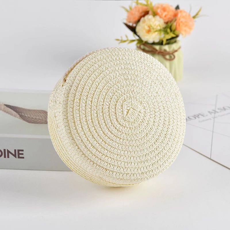 Round woven beige bag on a white surface with a blurred background