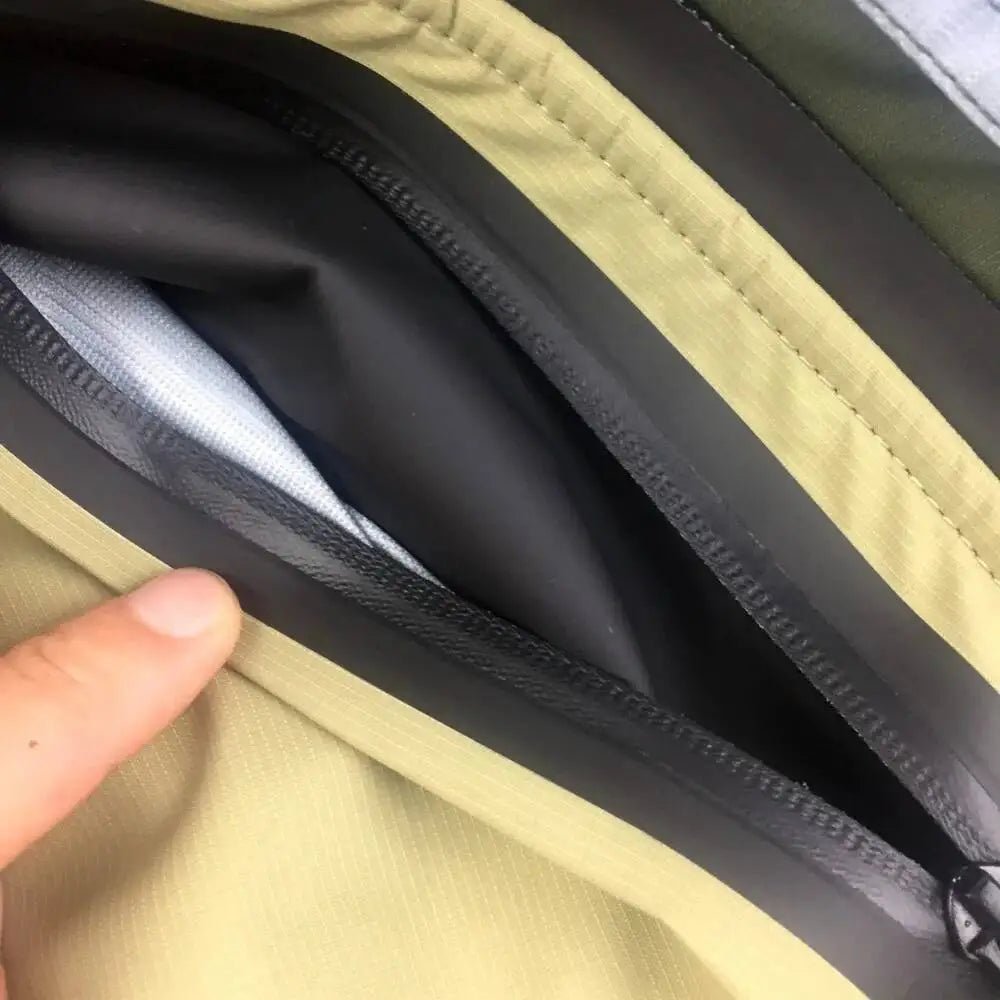 Close-up of a zipper on a jacket with a hand holding it open.