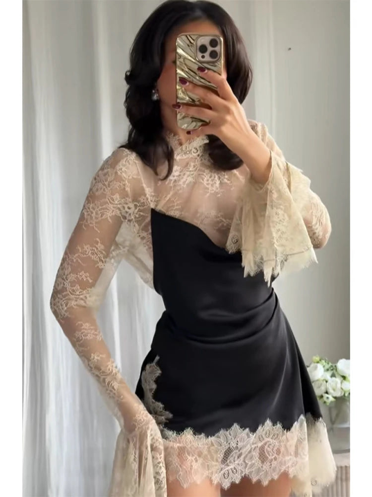 Person wearing a black dress with lace sleeves and hem, taking a mirror selfie.