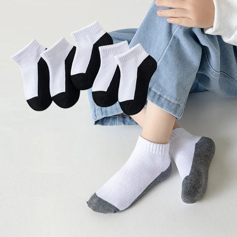 Person wearing white socks with black toes and gray soles, with additional pairs displayed.