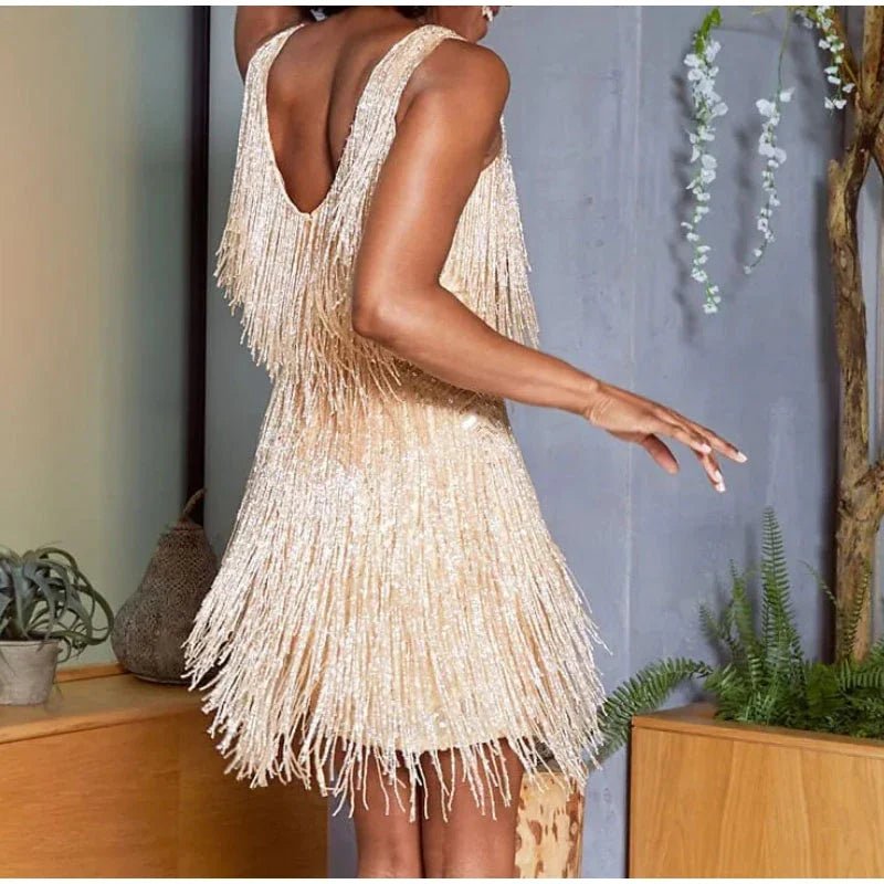Beige fringe dress worn by a person in an indoor setting with plants and a neutral wall.
