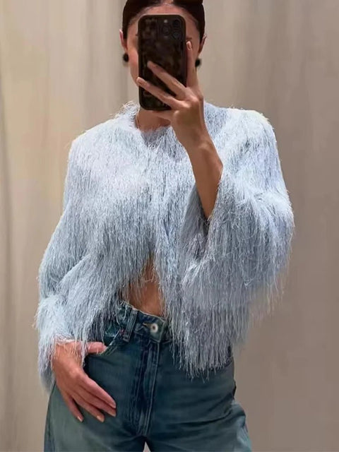 Person wearing a light blue fringed sweater and jeans, taking a mirror selfie.
