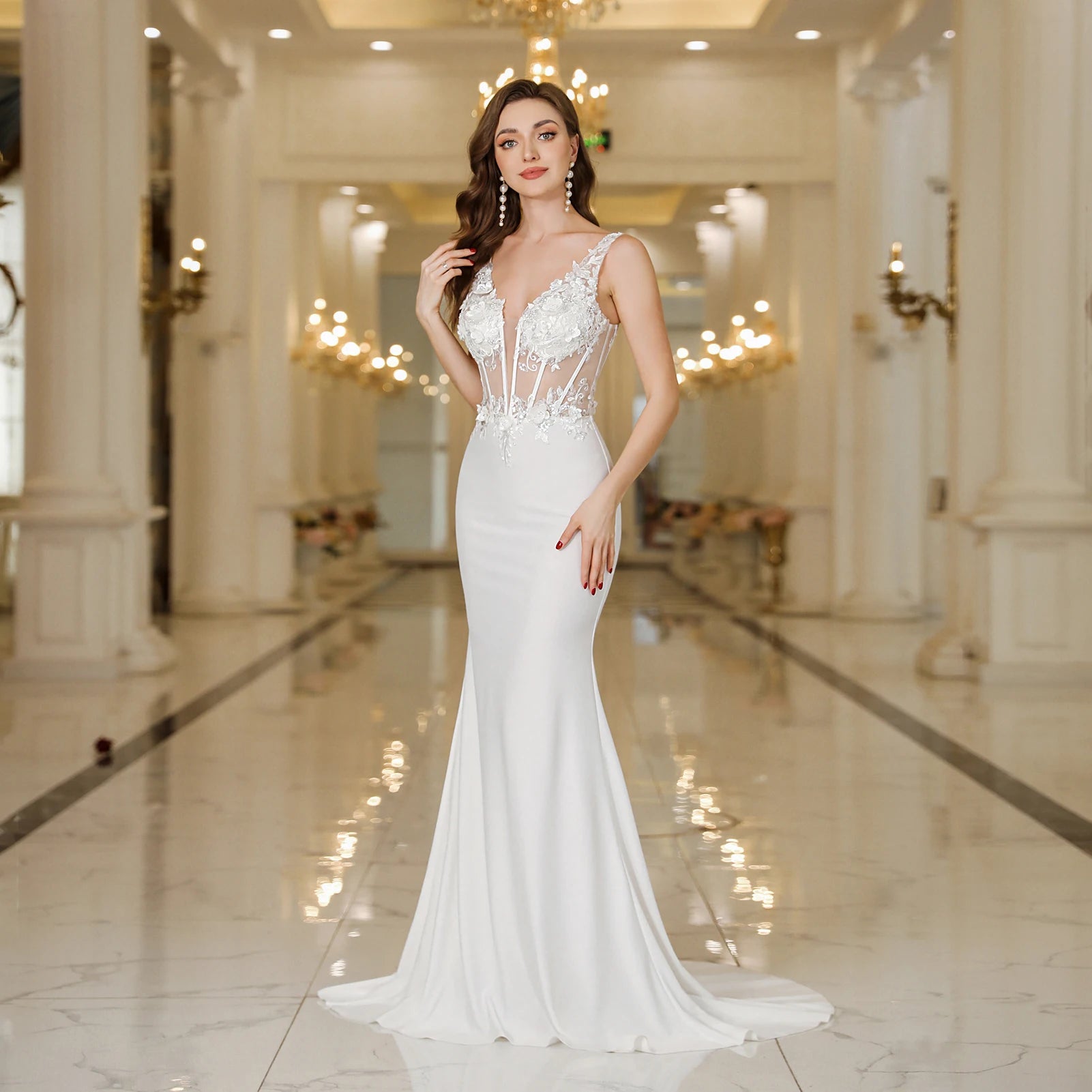 Woman in a white wedding dress standing in an elegant indoor setting.