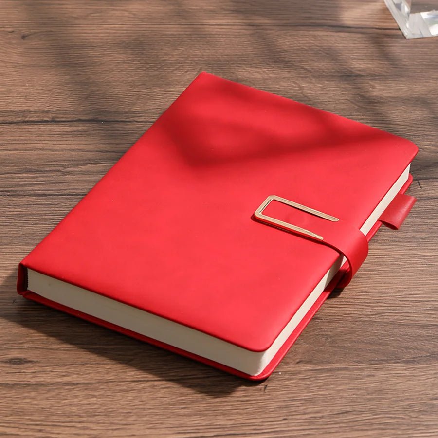 Red notebook with a gold buckle on a wooden surface