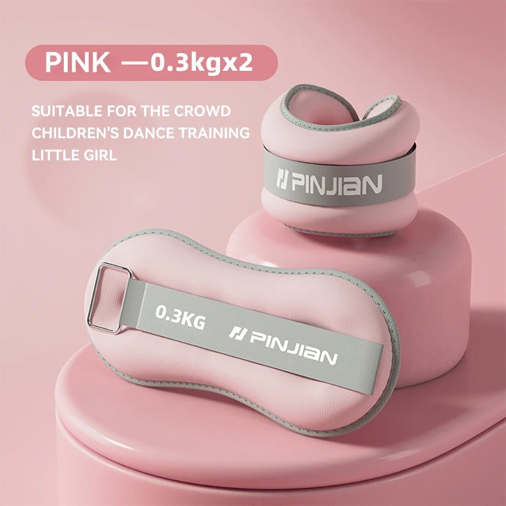 Pink ankle weights with gray straps on a pink background, suitable for children's dance training.