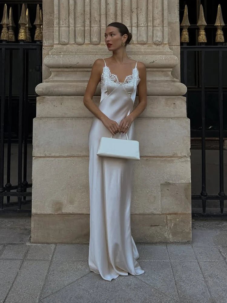 Woman in a white dress standing against a stone wall.