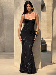Woman in a black evening gown standing against a stone wall.