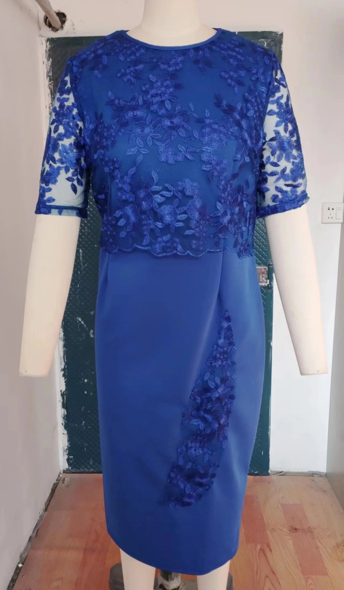 Blue lace dress on a mannequin against a plain background