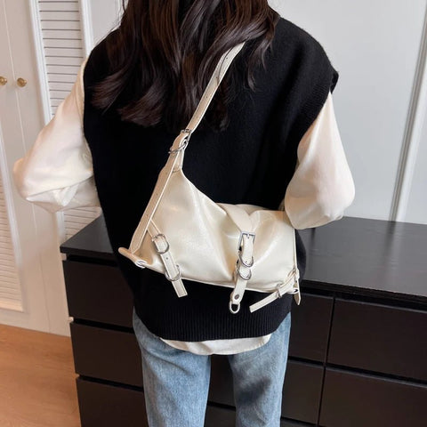Person wearing a black and white outfit with a beige handbag.