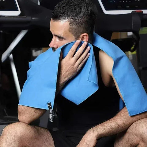 Man using a blue towel on his neck in a gym setting