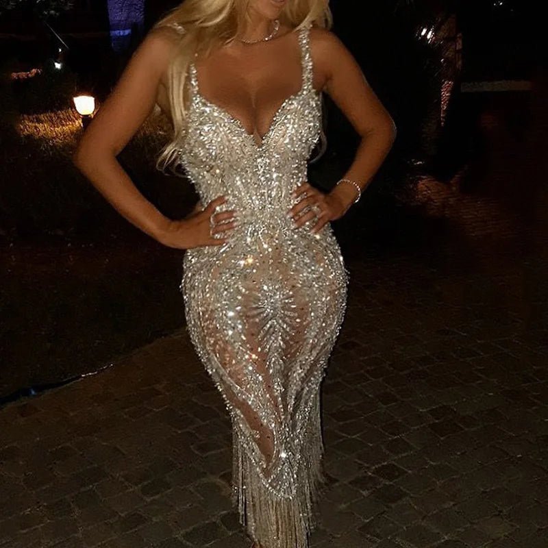 Woman wearing a sparkling silver dress with a deep neckline and slit on a dark background