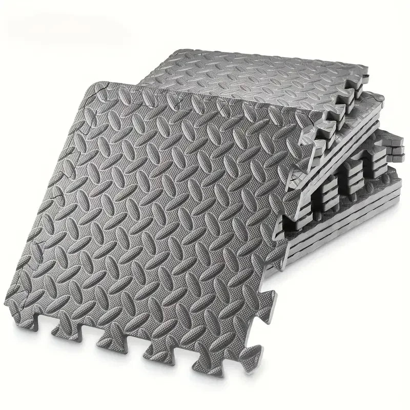 Stack of gray interlocking foam mats with diamond plate pattern on a white background