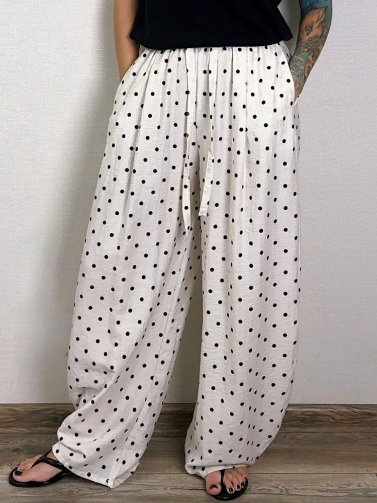 White pants with black polka dots worn by a person against a plain background