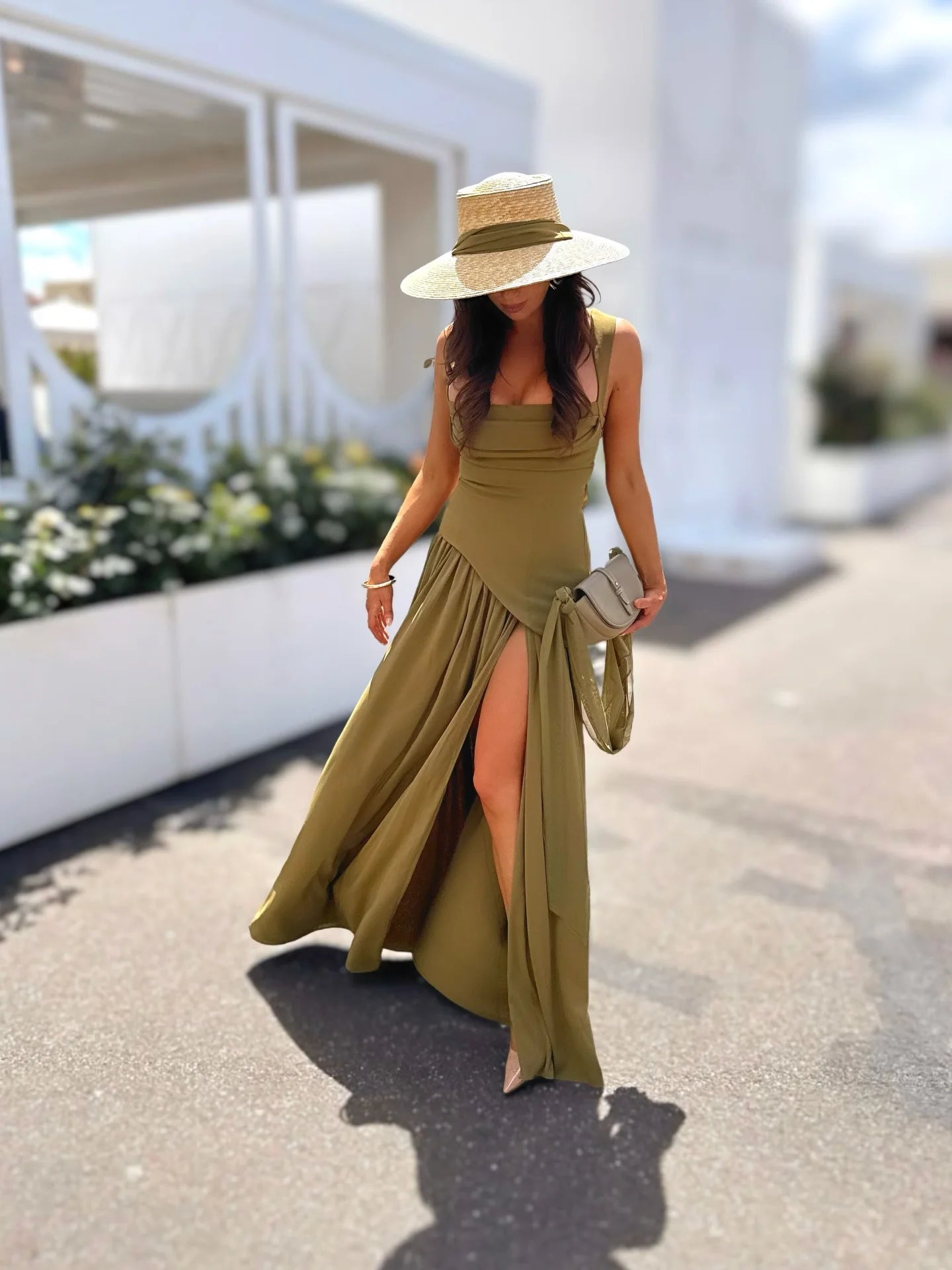 Woman in a long green dress and hat walking outdoors.