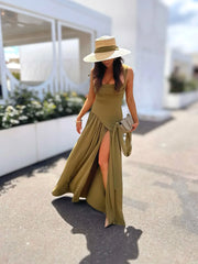 Woman in a long green dress and hat walking outdoors.
