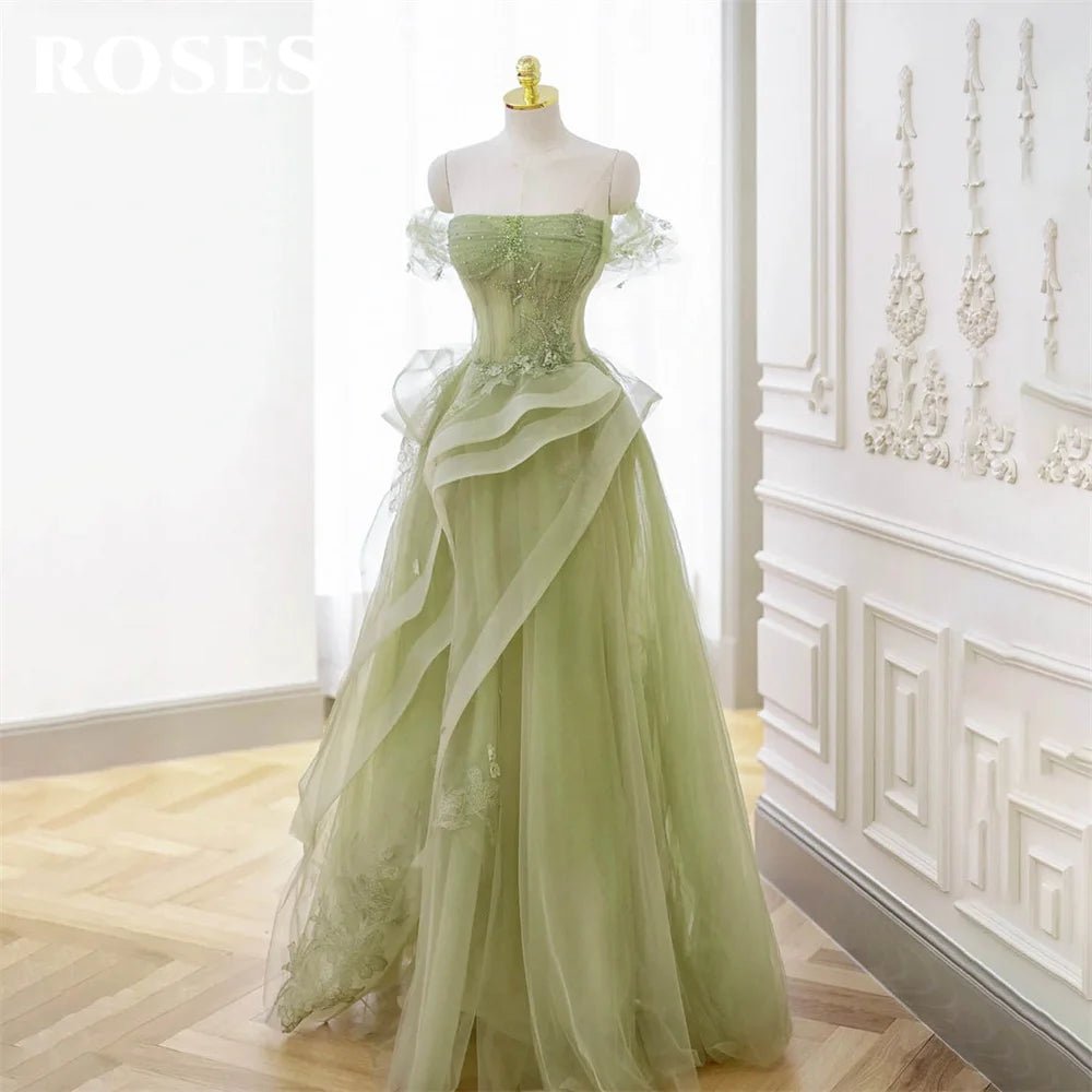 Green evening gown on a mannequin against a decorative wall.