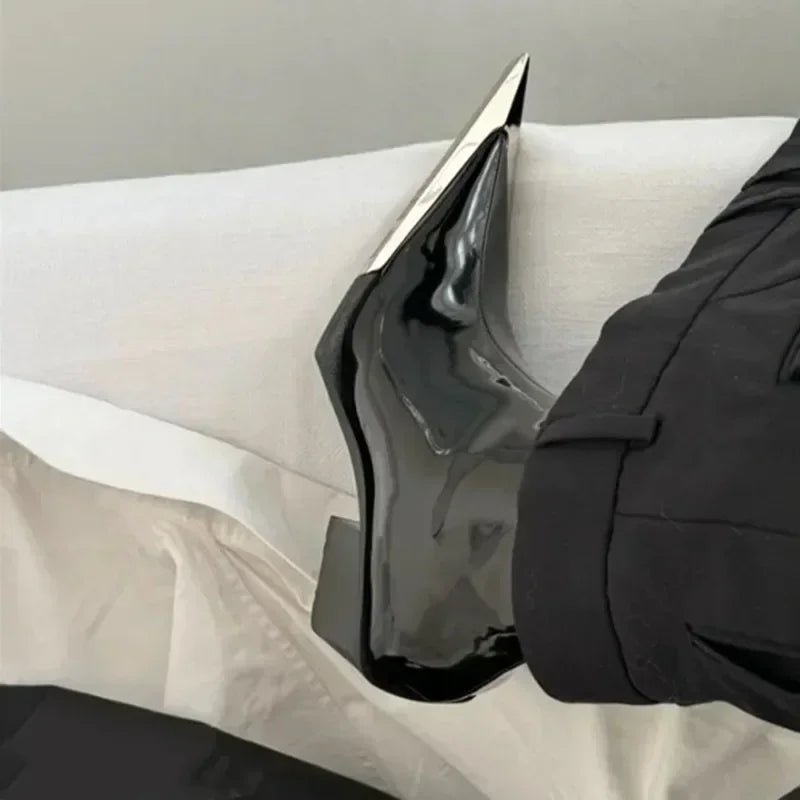 Black high-heeled shoe on a white surface with a neutral background