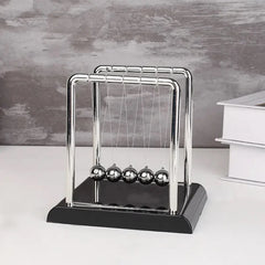 Newton's cradle on a white surface with a gray background
