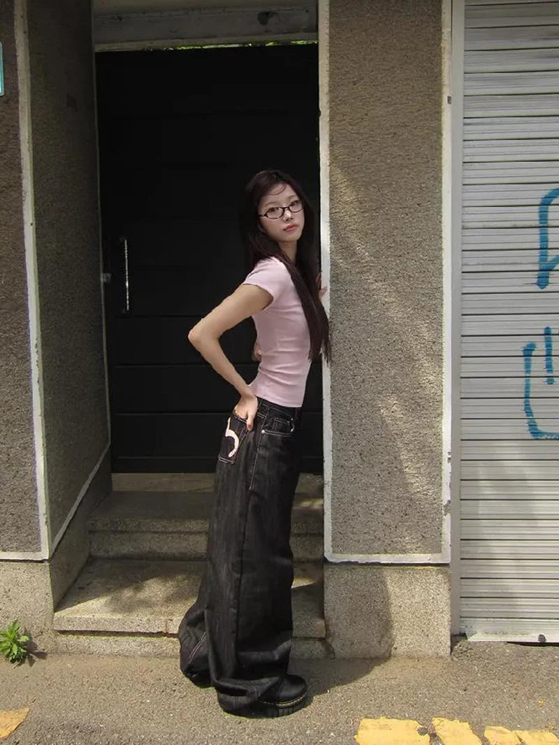 Person wearing a pink shirt and black pants standing in a doorway.