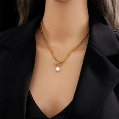 Gold necklace with a pearl pendant on a mannequin wearing a black outfit.
