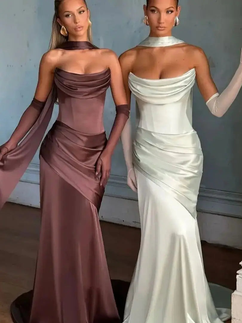 Two women in elegant evening gowns standing side by side against a neutral background.