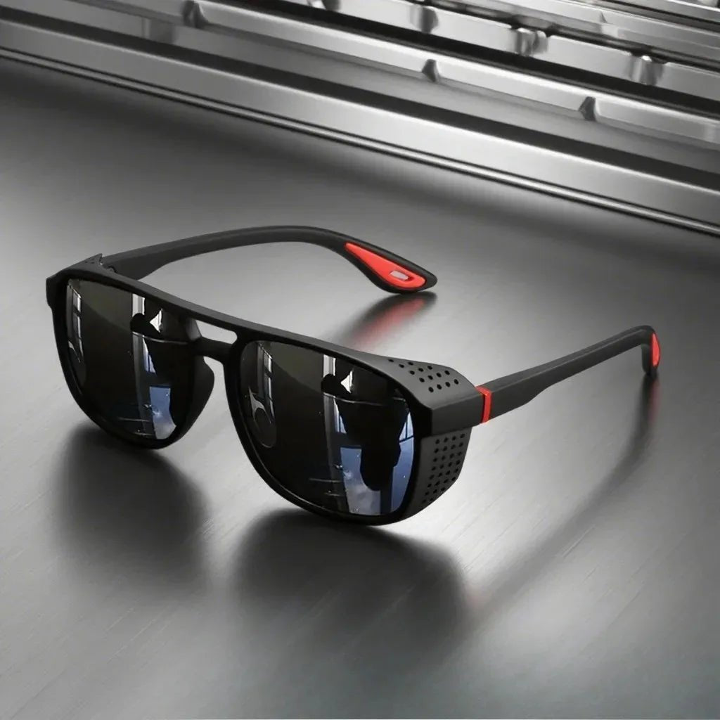 Black sunglasses with red accents on a reflective surface