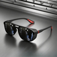 Black sunglasses with red accents on a reflective surface