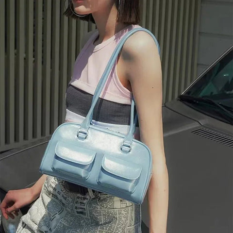 Person holding a light blue handbag in front of a car