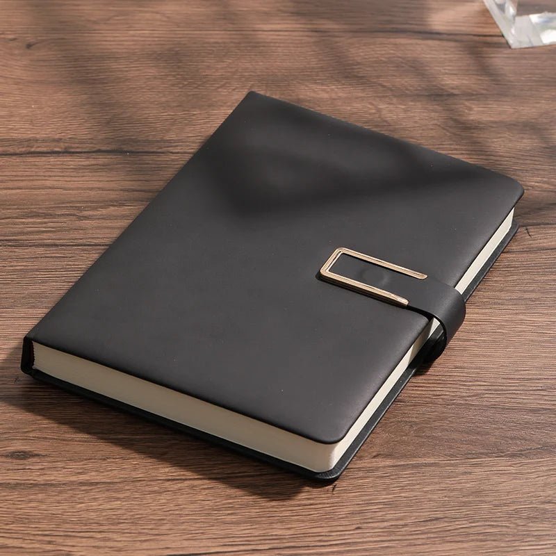 Black leather notebook with gold buckle on a wooden surface