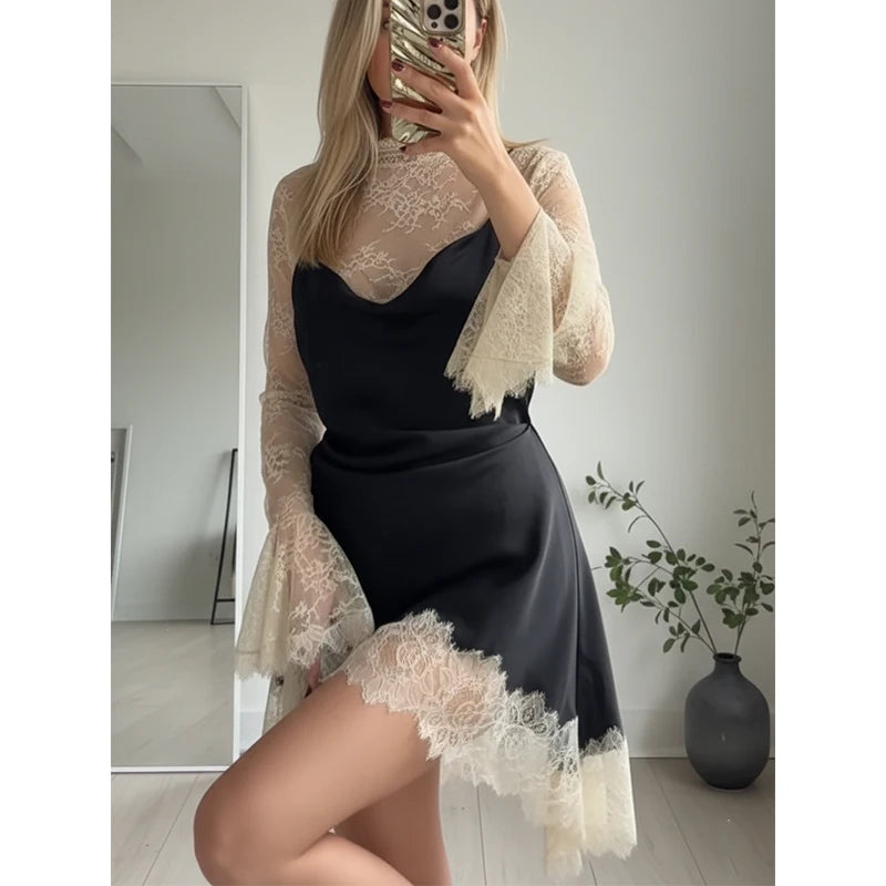 Person wearing a black outfit with beige lace sleeves and hem, standing in a room.