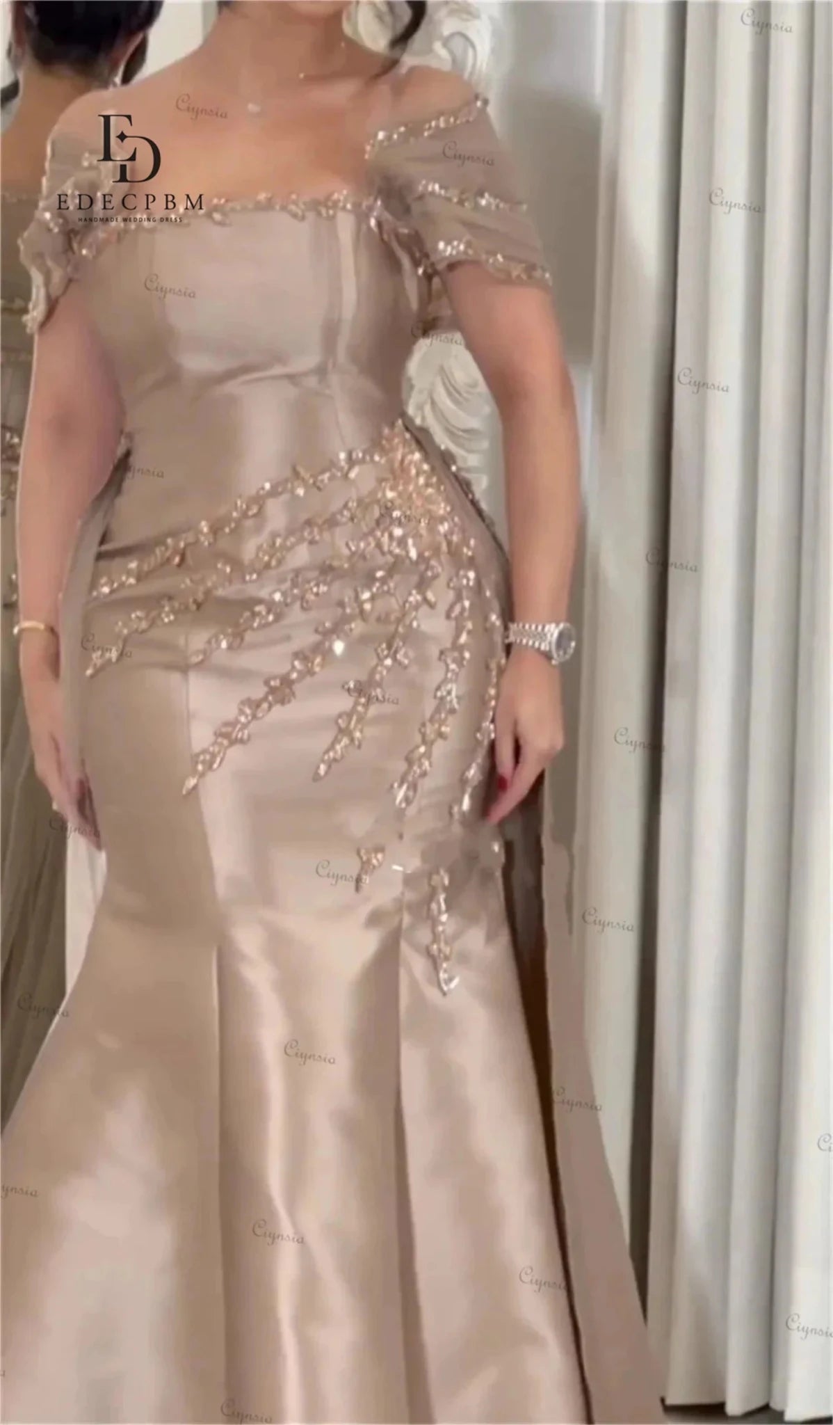 Beige evening gown with intricate beadwork on a neutral background