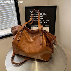 Brown leather handbag on a metallic surface with a blurred background